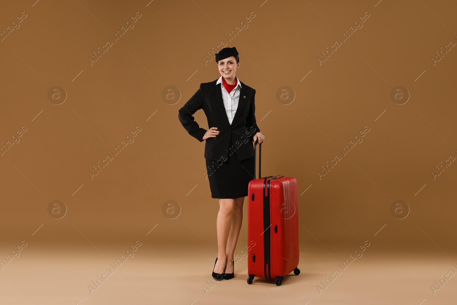 Photo of Smiling stewardess with suitcase on brown background