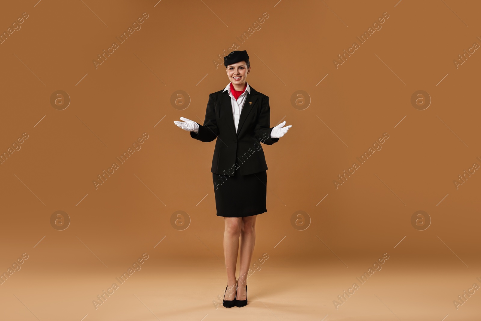 Photo of Smiling flight attendant demonstrating safety instruction on beige background