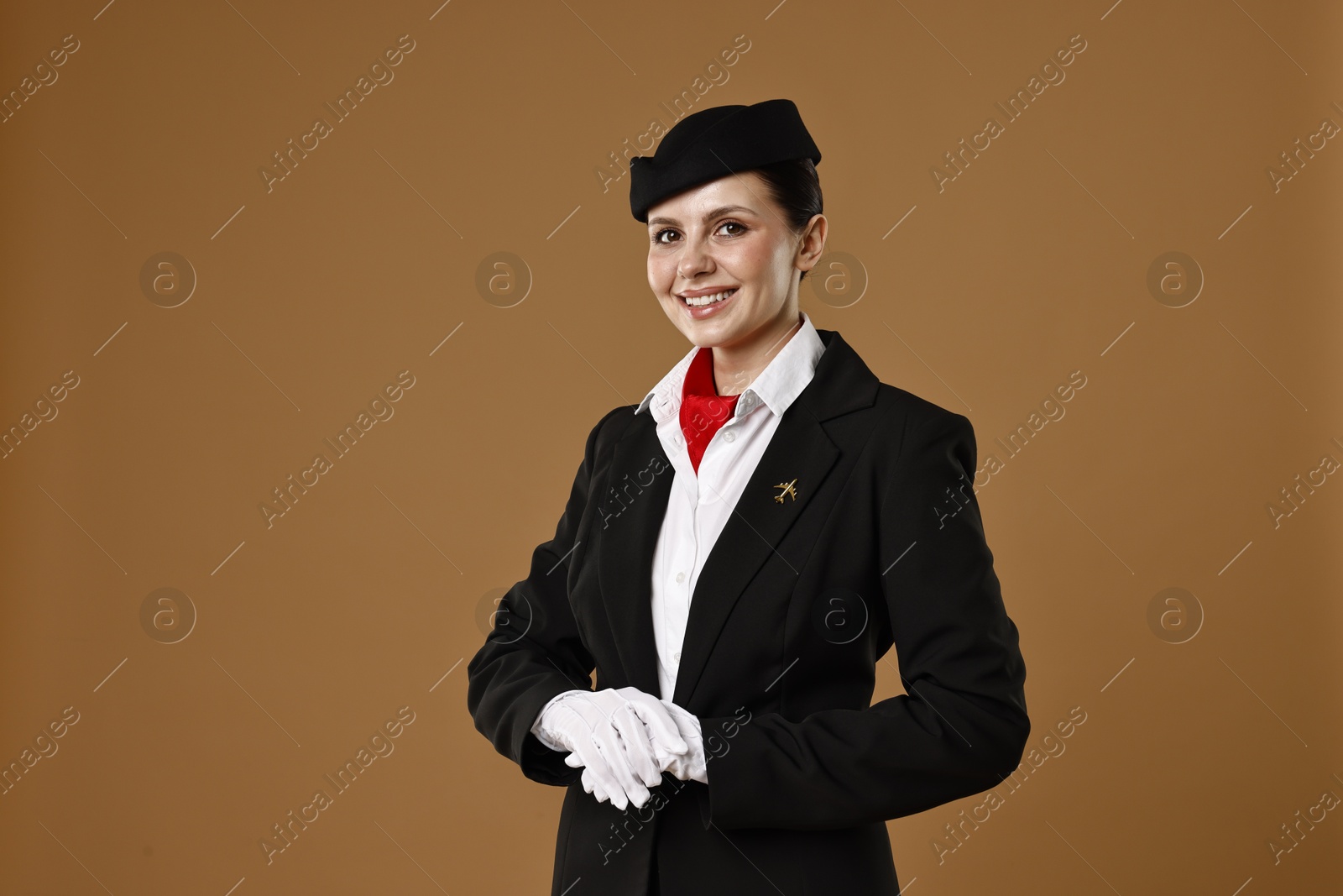 Photo of Smiling flight attendant on brown background. Space for text