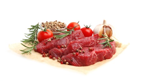 Photo of Pieces of raw beef meat, spices and tomatoes isolated on white