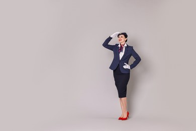 Photo of Smiling stewardess on grey background. Space for text