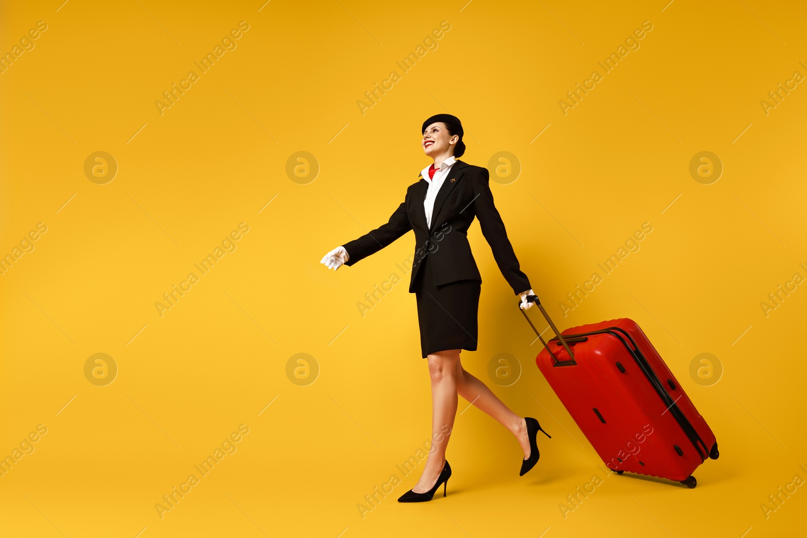 Photo of Happy flight attendant with suitcase on orange background, low angle view. Space for text