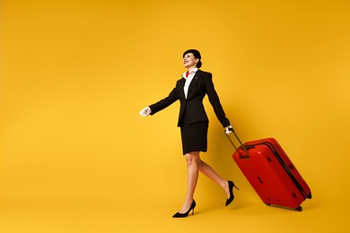 Happy flight attendant with suitcase on orange background, low angle view. Space for text