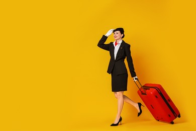 Photo of Happy flight attendant with suitcase on orange background. Space for text