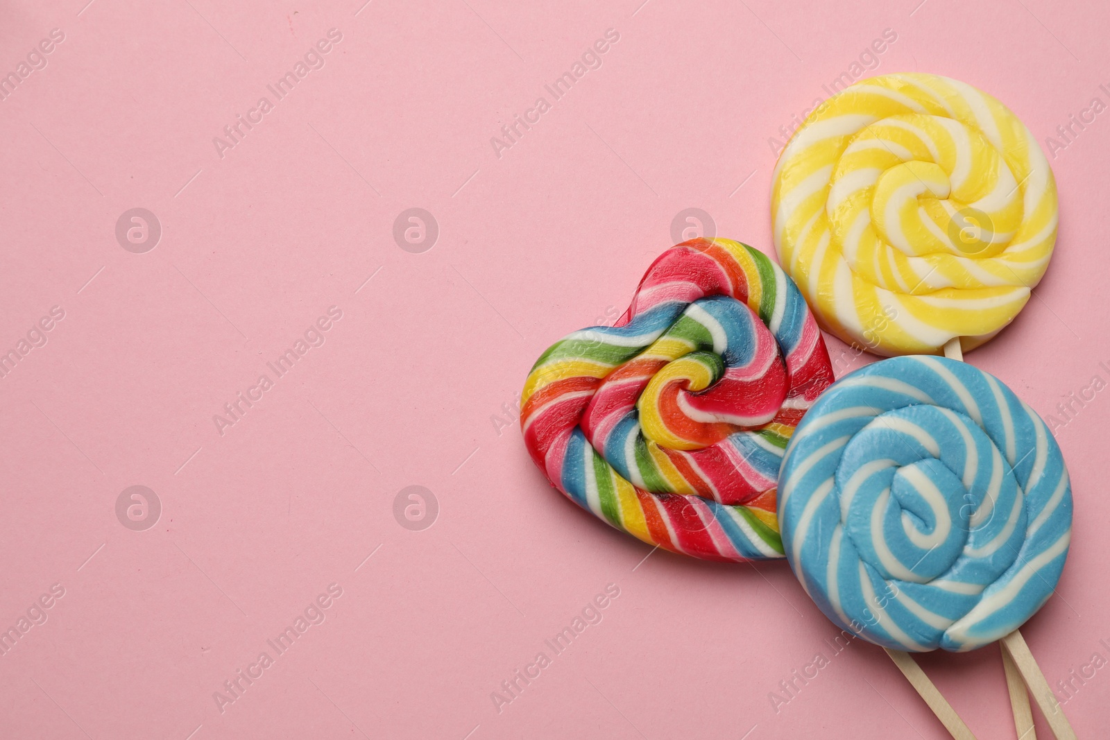 Photo of Tasty lollipops on pink background, flat lay. Space for text