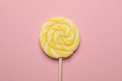 Photo of Tasty striped lollipop on pink background, top view