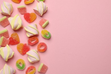 Photo of Many different tasty candies and marshmallows on pink background, flat lay