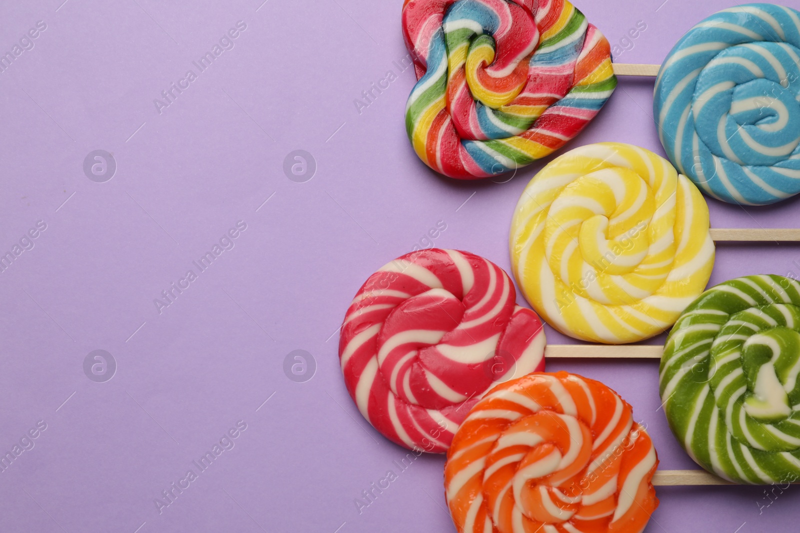 Photo of Tasty lollipops on violet background, flat lay. Space for text