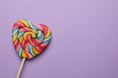 Photo of Tasty heart shaped lollipop on violet background, top view. Space for text