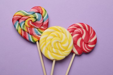 Tasty lollipops on violet background, flat lay