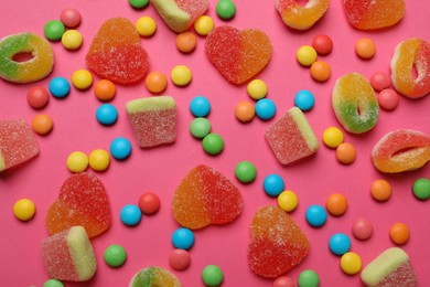 Many different tasty candies on bright pink background, flat lay