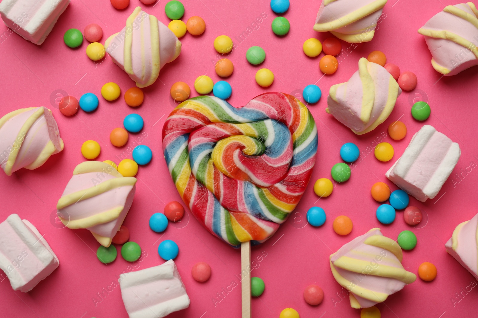 Photo of Many different tasty candies and marshmallows on pink background, flat lay