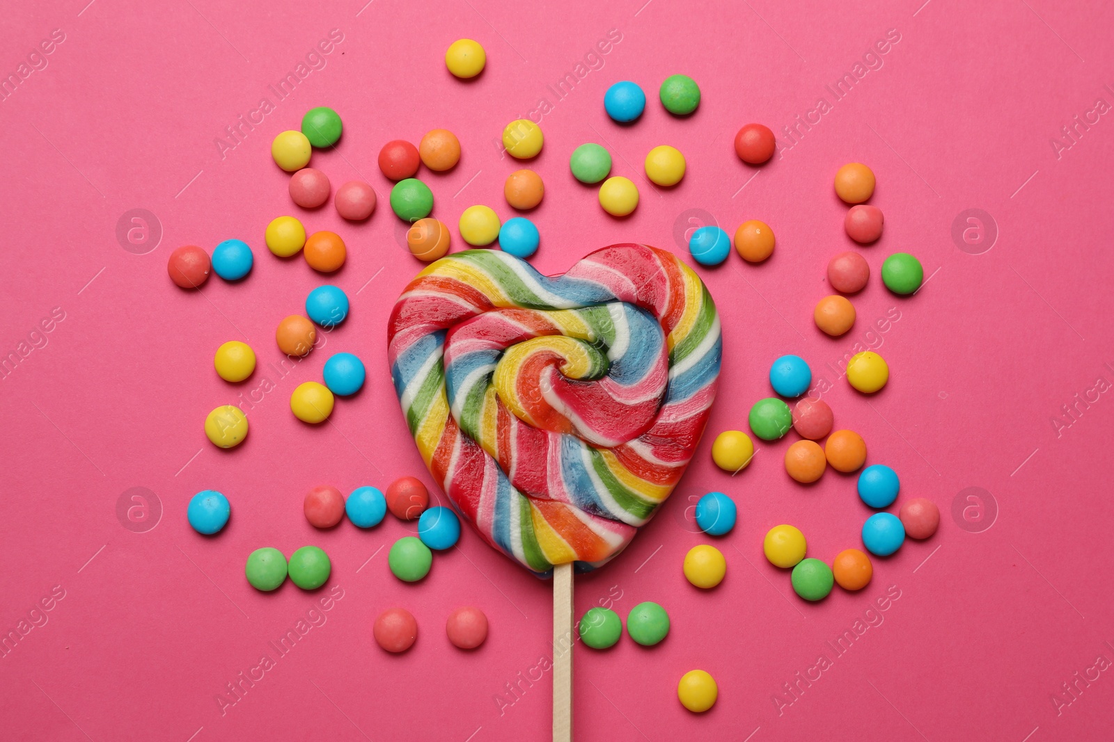 Photo of Many different tasty candies on pink background, flat lay