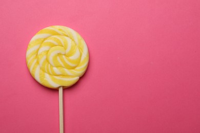 Photo of Tasty striped lollipop on bright pink background, top view. Space for text