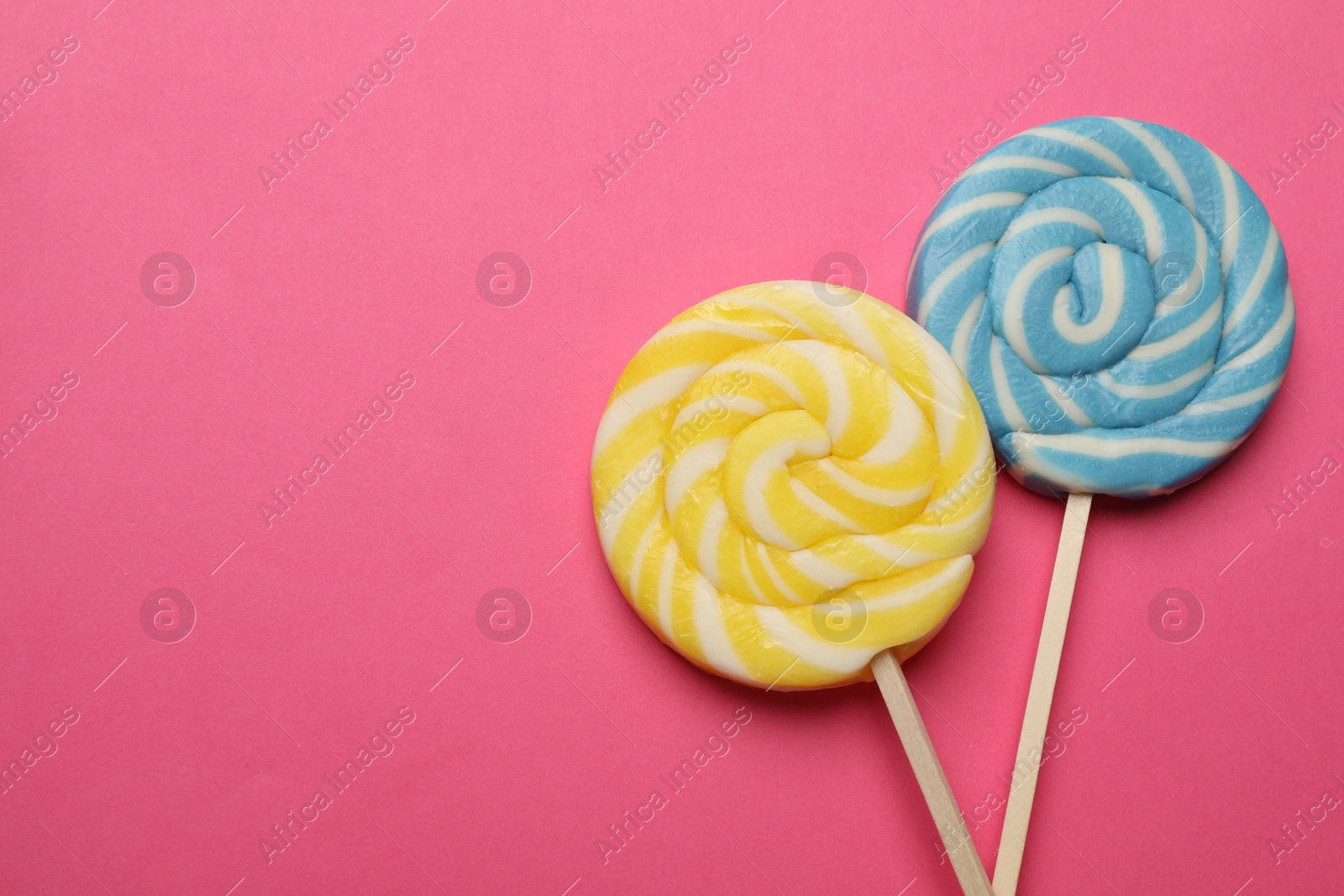 Photo of Tasty lollipops on bright pink background, flat lay. Space for text