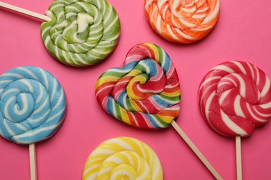 Photo of Tasty lollipops on bright pink background, flat lay