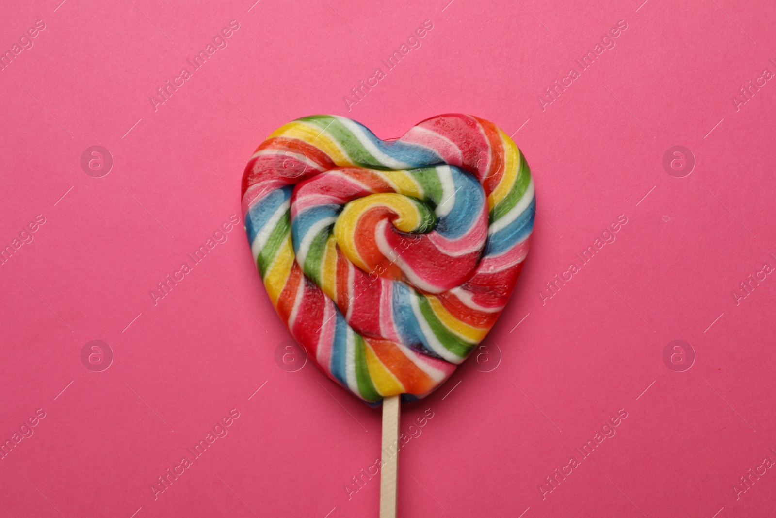 Photo of Tasty heart shaped lollipop on bright pink background, top view