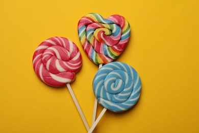 Tasty lollipops on yellow background, flat lay