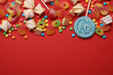 Photo of Many different tasty candies and marshmallows on red background, flat lay. Space for text