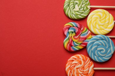 Photo of Tasty lollipops on red background, flat lay. Space for text