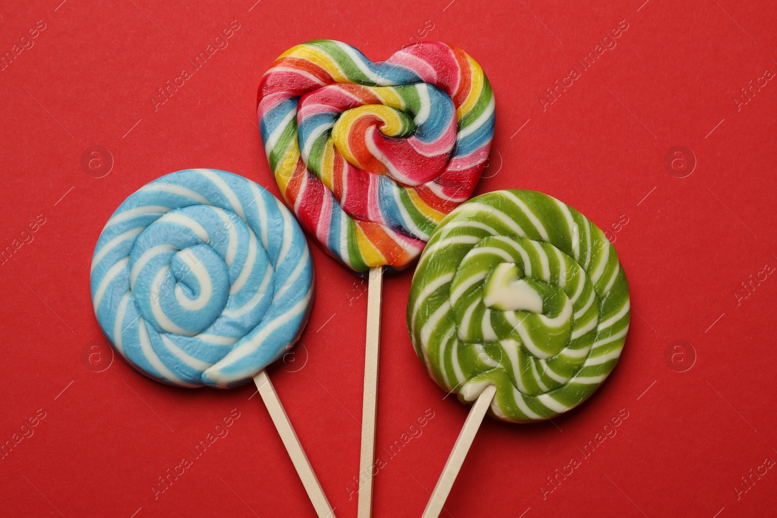 Photo of Tasty lollipops on red background, flat lay