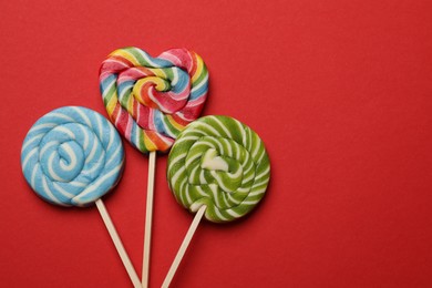 Photo of Tasty lollipops on red background, flat lay. Space for text