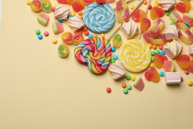 Photo of Many different tasty candies and marshmallows on beige background, flat lay. Space for text