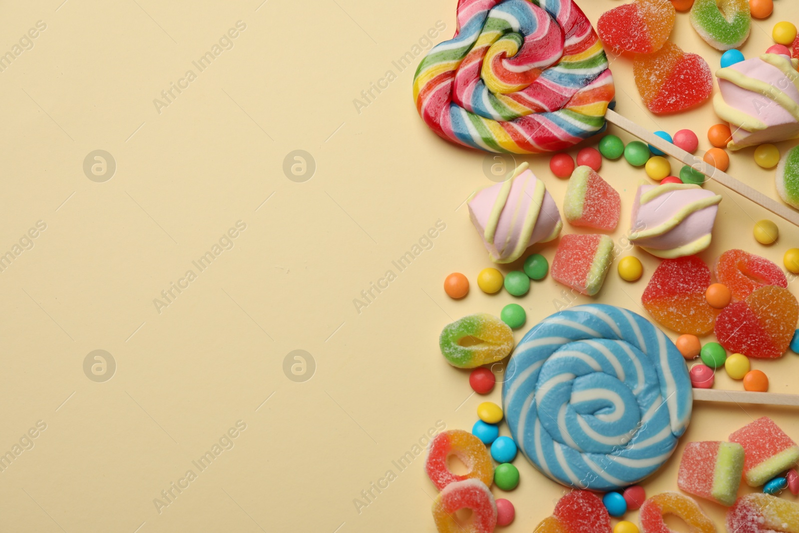 Photo of Many different tasty candies and marshmallows on beige background, flat lay. Space for text