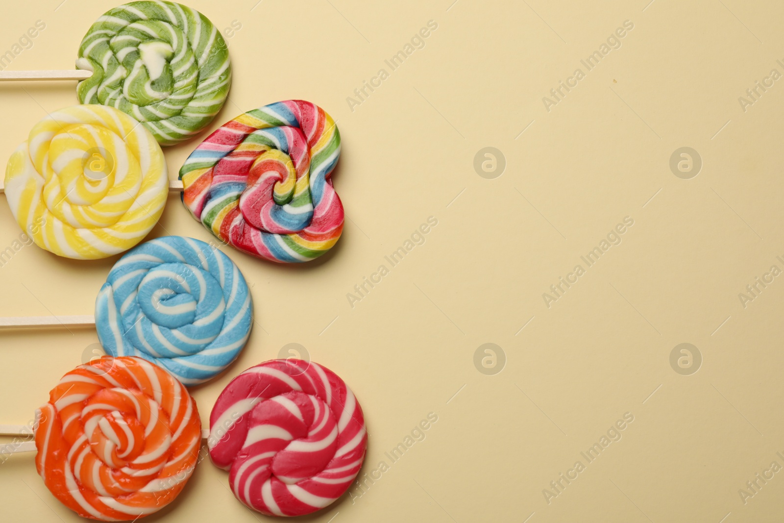 Photo of Tasty lollipops on beige background, flat lay. Space for text