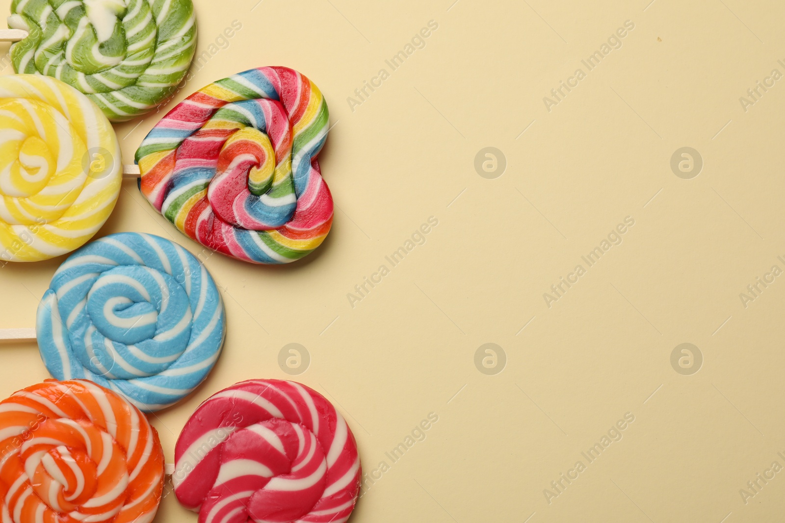 Photo of Tasty lollipops on beige background, flat lay. Space for text