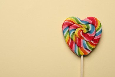 Photo of Tasty heart shaped lollipop on beige background, top view. Space for text