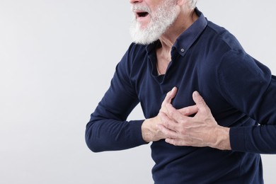 Photo of Heart attack. Senior man suffering from pain in chest on light background, closeup. Space for text