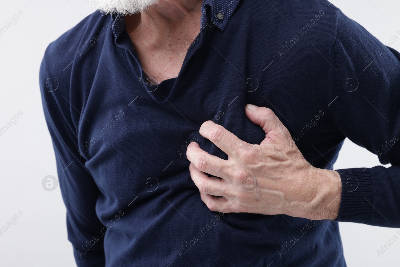 Photo of Heart attack. Senior man suffering from pain in chest on light background, closeup