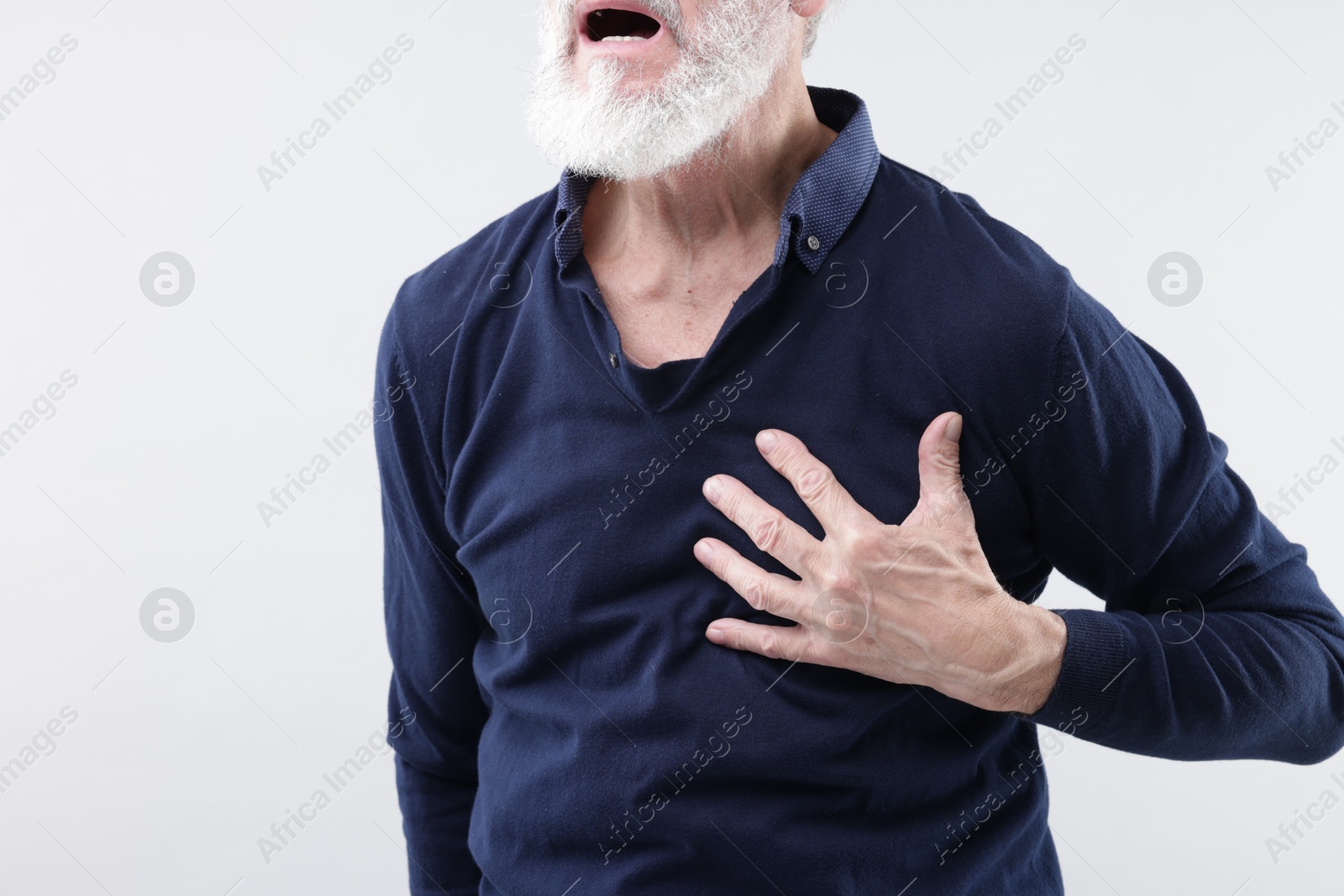 Photo of Heart attack. Senior man suffering from pain in chest on light background, closeup