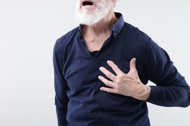 Photo of Heart attack. Senior man suffering from pain in chest on light background, closeup