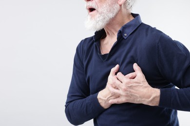 Photo of Heart attack. Senior man suffering from pain in chest on light background, closeup. Space for text