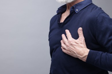 Photo of Heart attack. Senior man suffering from pain in chest on grey background, closeup. Space for text