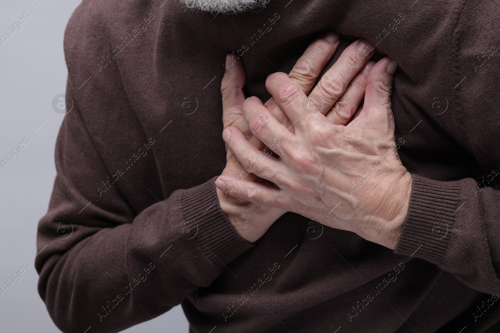 Photo of Heart attack. Senior man suffering from pain in chest on grey background, closeup