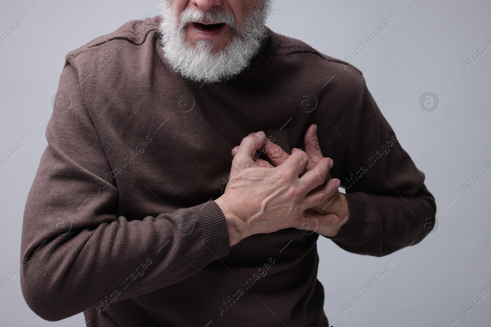 Photo of Heart attack. Senior man suffering from pain in chest on grey background, closeup