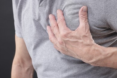 Photo of Heart attack. Senior man suffering from pain in chest on grey background, closeup