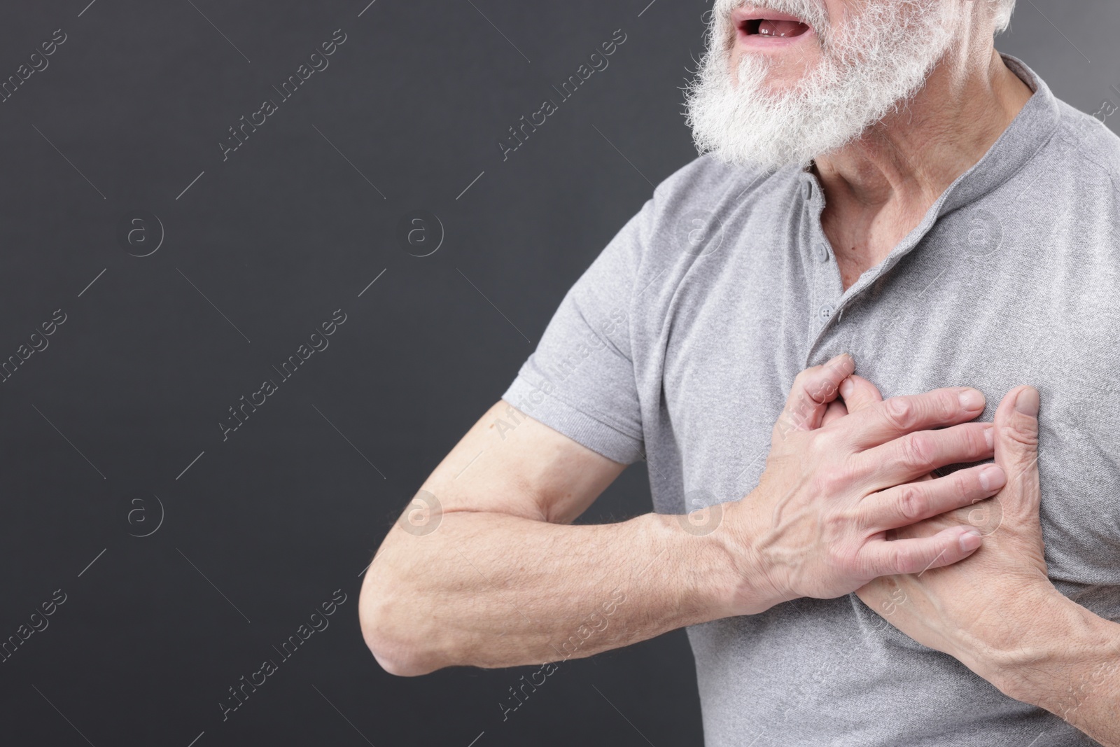 Photo of Heart attack. Senior man suffering from pain in chest on grey background, closeup. Space for text