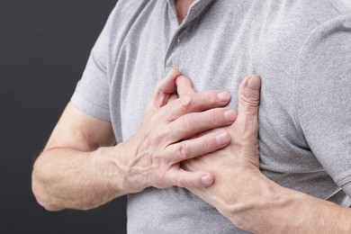 Photo of Heart attack. Senior man suffering from pain in chest on grey background, closeup