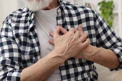 Photo of Heart attack. Senior man suffering from pain in chest at home, closeup