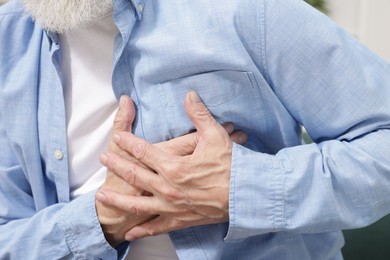 Photo of Heart attack. Senior man suffering from pain in chest at home, closeup