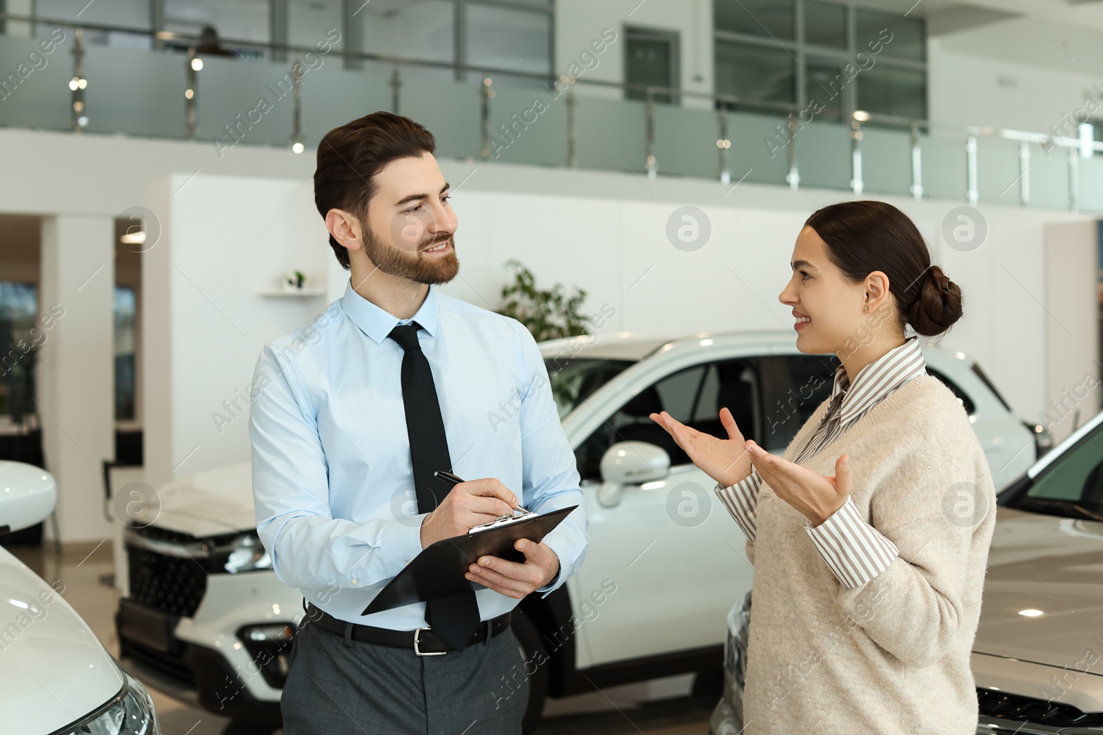 Photo of Happy salesman and client near new car in salon