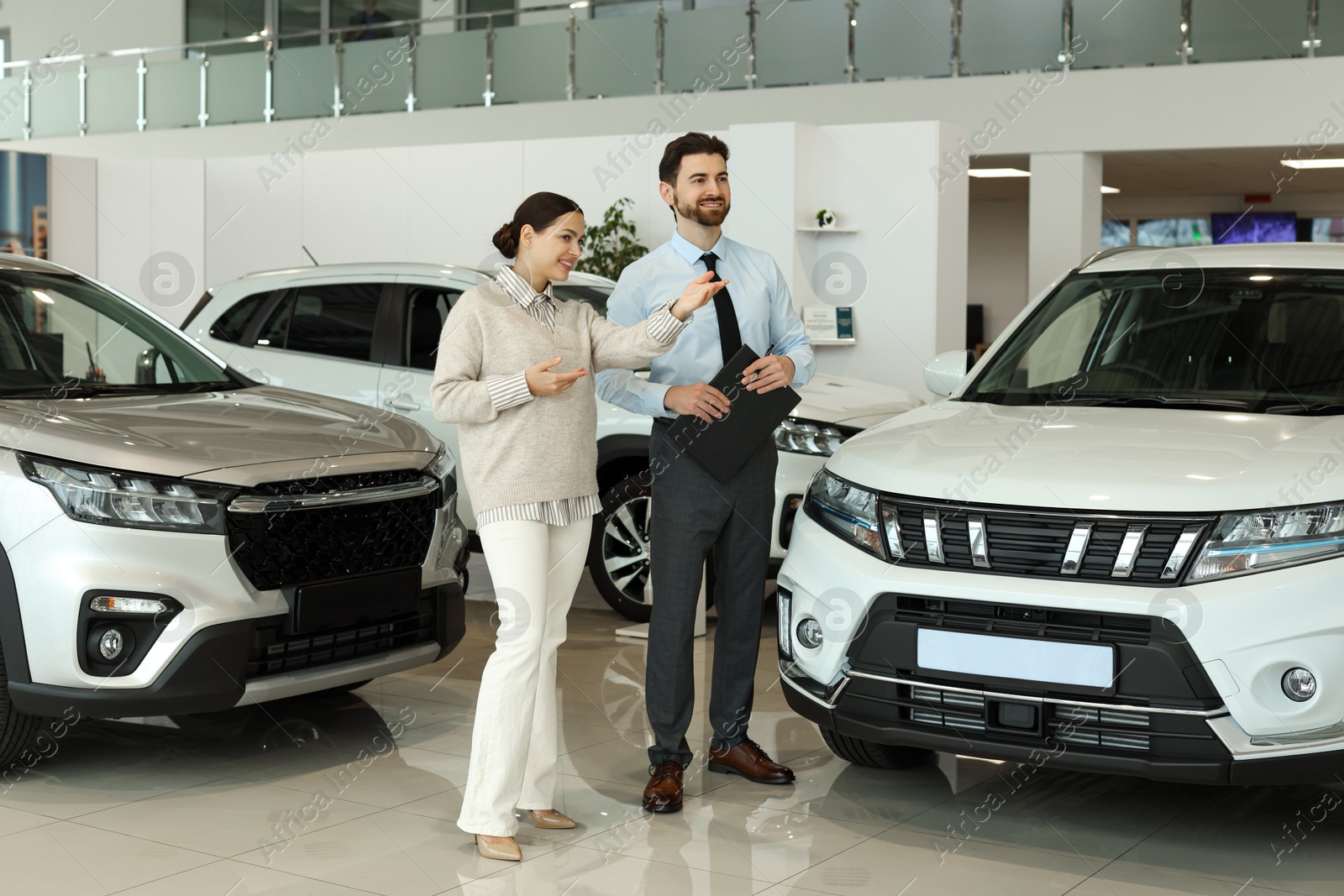 Photo of Happy salesman and client near new car in salon