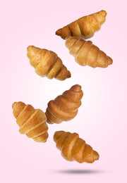 Image of Delicious croissants falling on pink background. Puff pastry