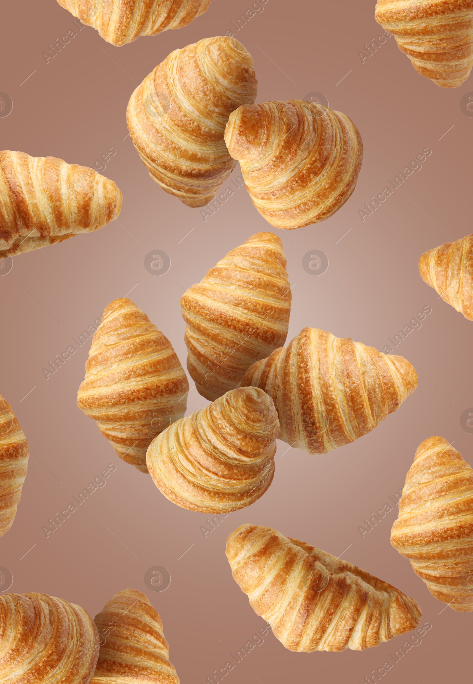 Image of Delicious croissants in air on pale brown background. Puff pastry