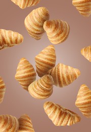 Image of Delicious croissants in air on pale brown background. Puff pastry