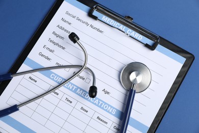 Photo of Stethoscope and medical card form on blue background, top view